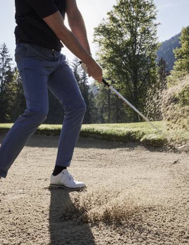 Person bewegt den Golfball aus einer Sandgrube