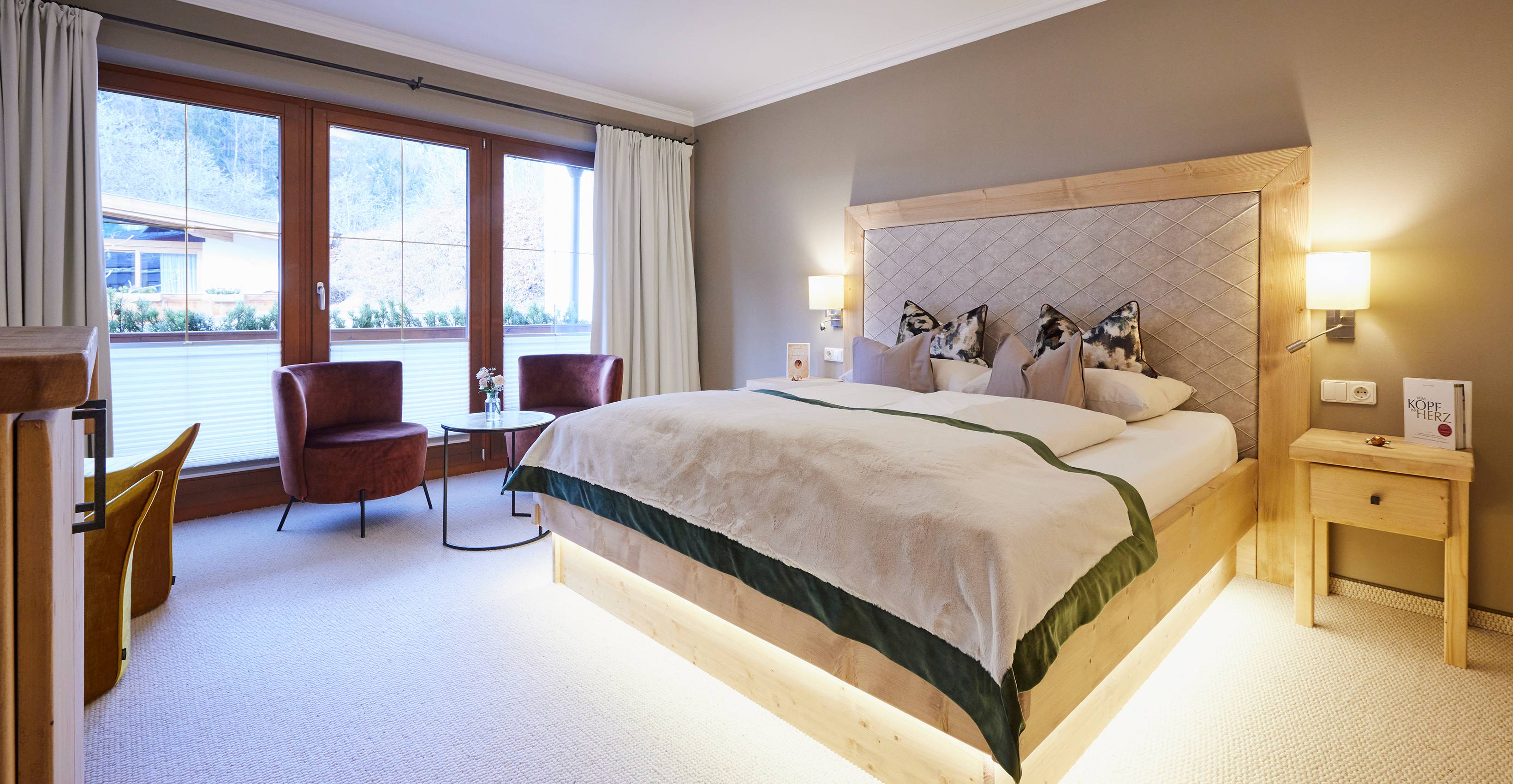 Helles Hotelzimmer mit Ausblick in den Garten Wandfarbe im Erdton und Schaffoldteppich auch für Allergiker geeignet