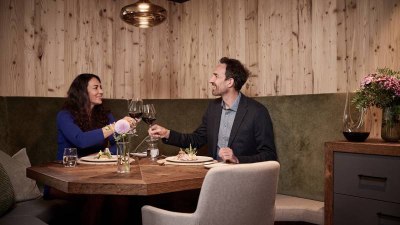 Pärchen im modernen Restaurant beim Essen - Sie stoßen mit einem Glas Rotwein an
