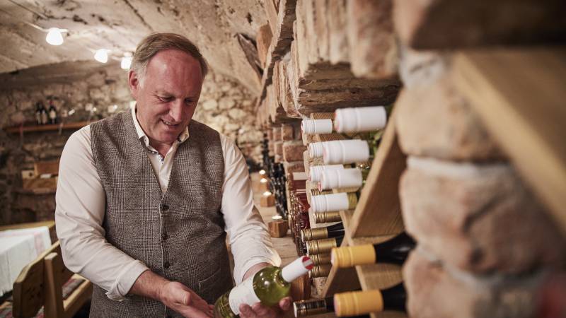 Hotelbesitzer hält im Weinkeller Wein in der Hand