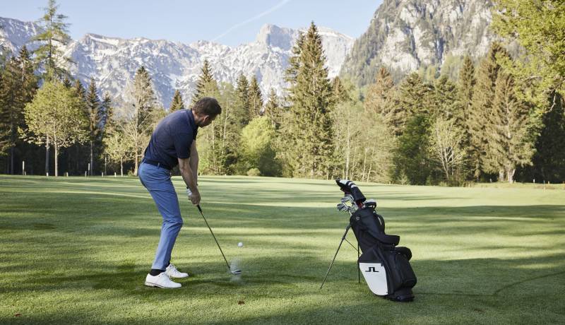 Person auf Golfplatz mit Bergpanorama